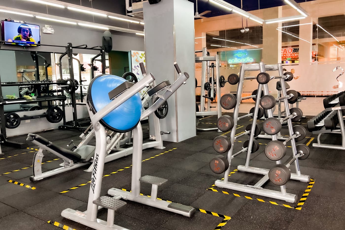 A gym floor with strength machines and weight racks under bright lights