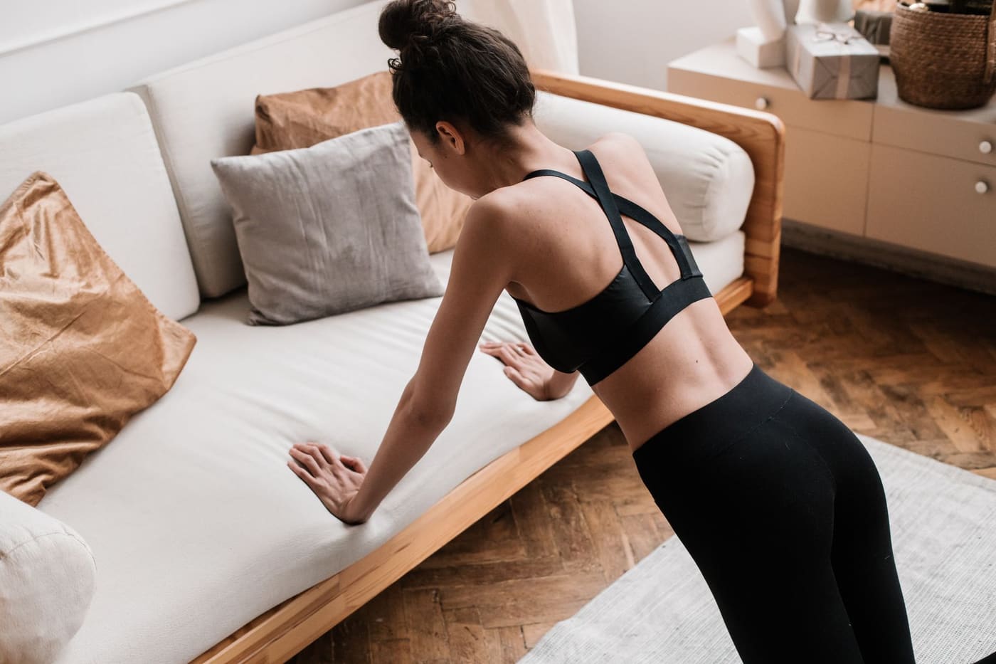 A woman doing an incline push-up with her hands on a sofa in a living room