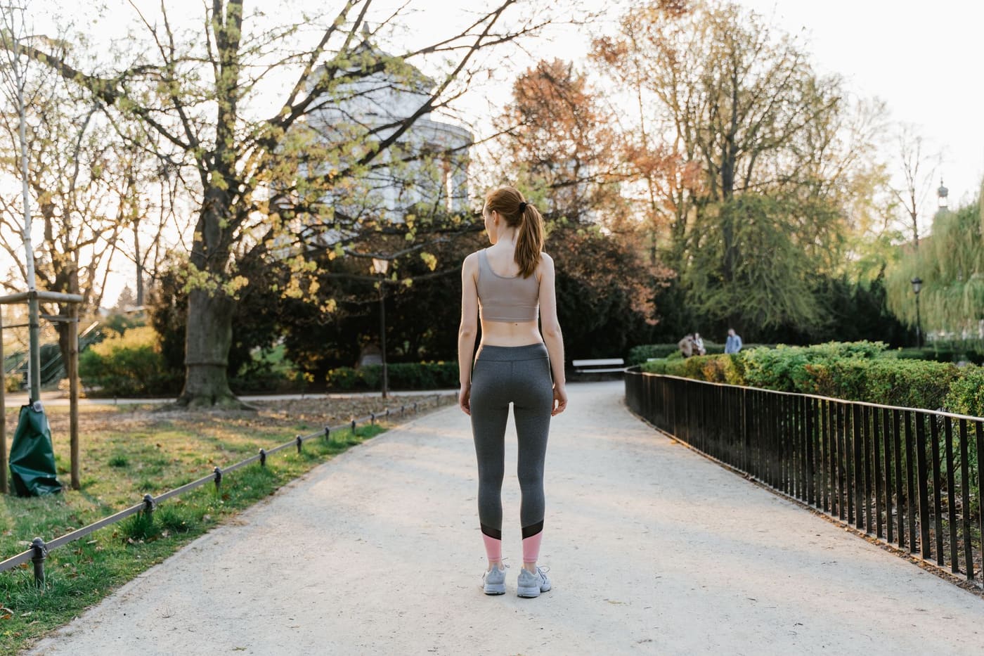 A person in activewear walking along a sunny park path